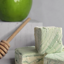 Load image into Gallery viewer, Three square bars of marbled green and cream marshmallows stacked on a light surface, with a wooden honey dipper and a green apple in the softly blurred background.