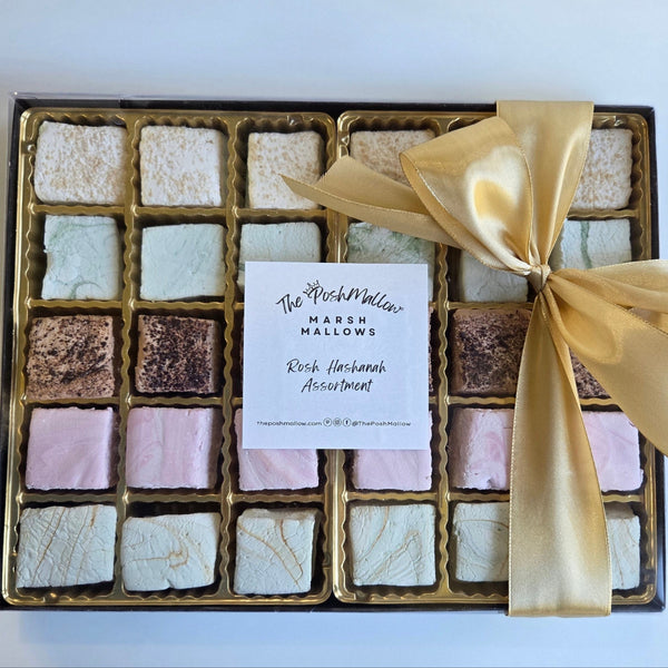Box of assorted marshmallows with a gold ribbon on a white background